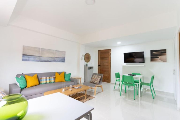 Sala de estar y comedor moderno con sillas verdes y sofá gris en Landa Mar Boca Chica