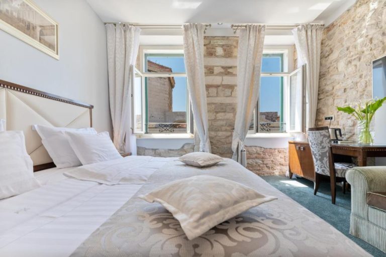 Habitación doble con pared de piedra y ventanas abiertas en Heritage Hotel Antique Split