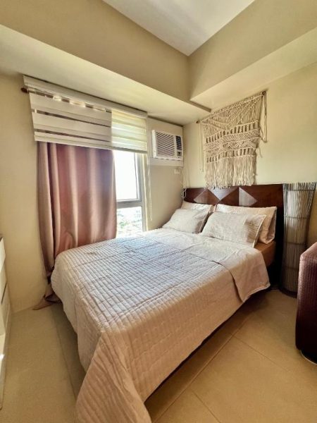 Habitación con cama doble y decoración boho en Cozy Studio Cebu IT Park con aire acondicionado