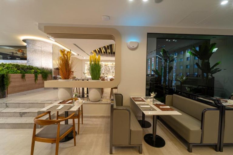 Restaurante interior moderno del Hill Top Hotel con mesas elegantes, sofás y decoración con plantas naturales