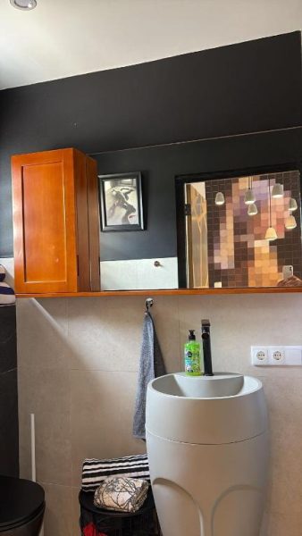 Baño moderno con lavabo cilíndrico blanco y decoración en negro del Thuishaven Boutique Mini-Resort