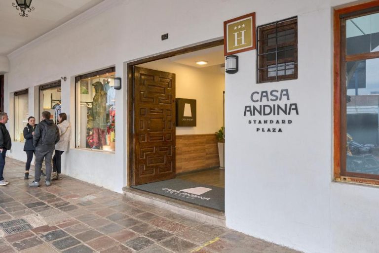 Entrada principal del hotel Casa Andina Standard Cusco Plaza con puerta de madera tallada y fachada blanca