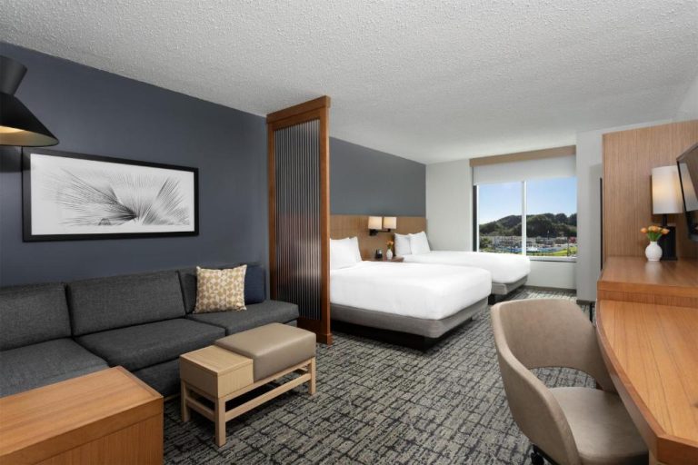 Suite con dos camas dobles y zona de estar con sofá en Hyatt Place Manatí, con vistas exteriores