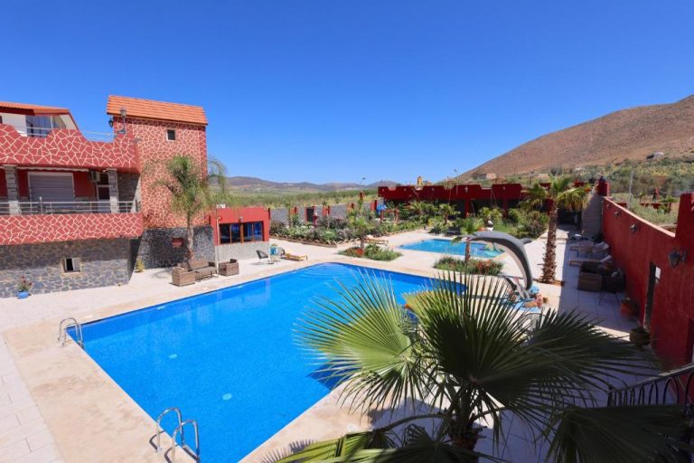 Piscina exterior con jardín tropical y vistas a la montaña del Palais D'orient en Marruecos
