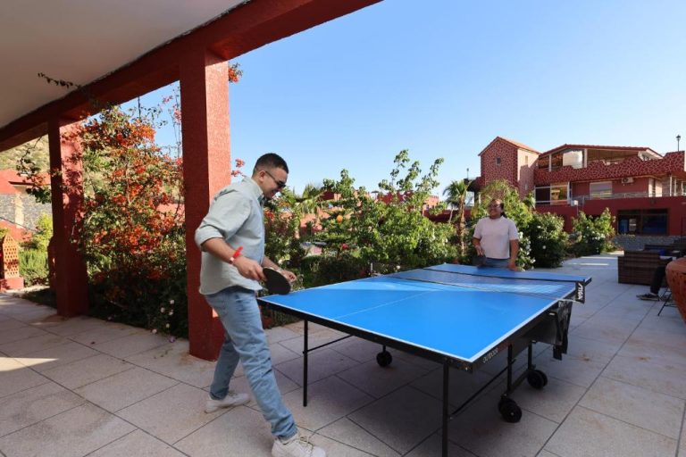 Dos huéspedes jugando al ping pong en la terraza exterior del Palais D'orient rodeada de jardines