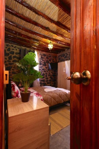 Habitación rústica del Palais D'orient con techo de caña, paredes de piedra y cama doble acogedora