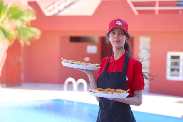 Camarera del Palais D'orient sirviendo pizzas junto a la piscina exterior del hotel