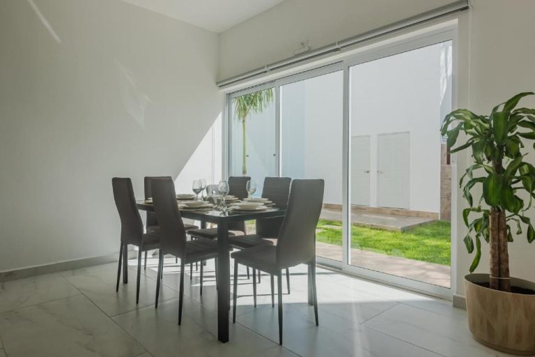 Comedor moderno con mesa de cristal y sillas oscuras con vistas al jardín en Malibu Residential 3BD Shalva
