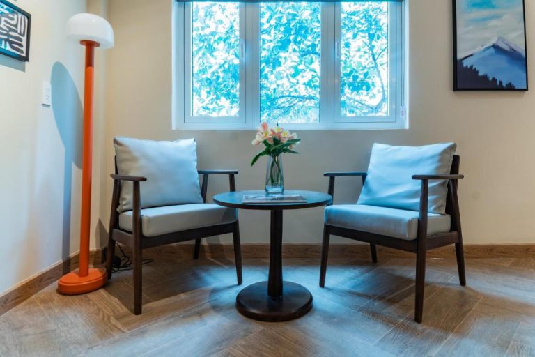 Sala de estar con dos sillones azules y mesa redonda junto a ventana en Anise Luxe Home