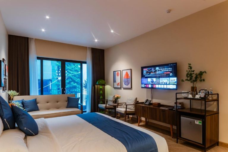 Habitación deluxe con cama matrimonial, sofá azul y smart TV en Anise Luxe Home