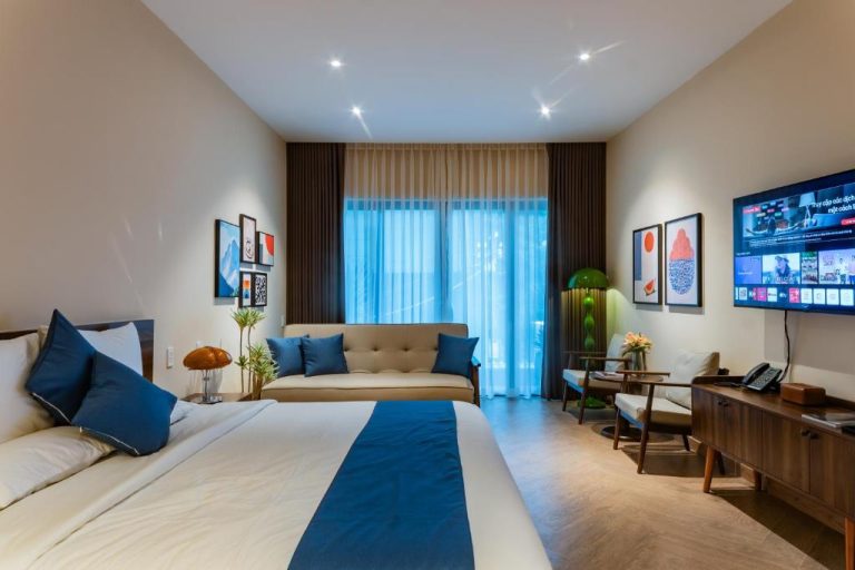 Habitación deluxe con cama matrimonial y sofá azul en Anise Luxe Home