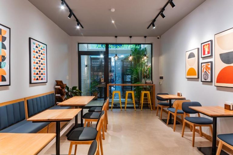 Restaurante interior moderno del Anise Luxe Home con mesas de madera, sofás azules y arte decorativo en las paredes
