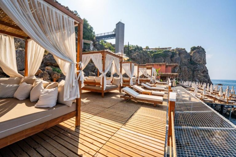 Terraza de playa con camas balinesas y tumbonas frente al mar en Massimo Hotel Adults Only