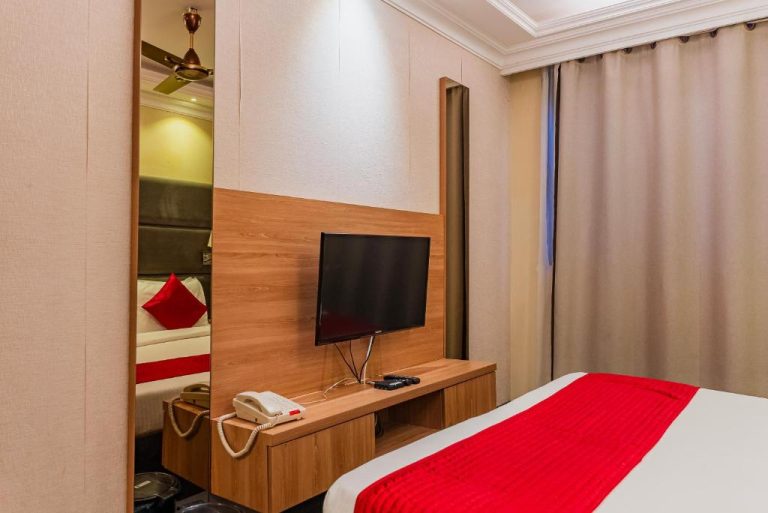 Habitación doble con televisión y cama en Coral Grand Beach & Spa con decoración en rojo