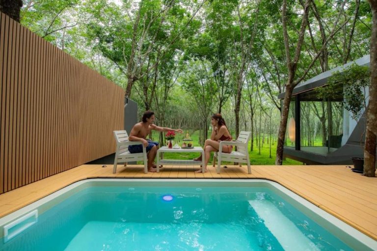 Pareja disfrutando de la piscina privada con terraza de madera rodeada de naturaleza en Timber Society Boutique Hideaway
