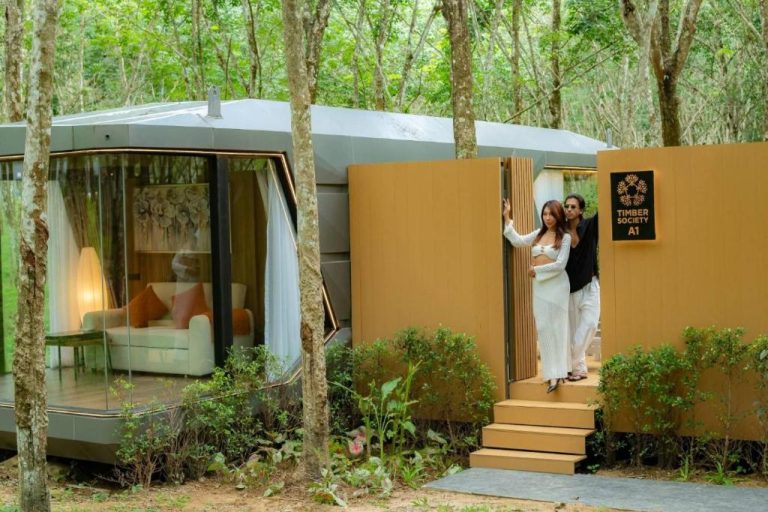 Pareja en la entrada de una cabana de cristal en el bosque del Timber Society Boutique Hideaway