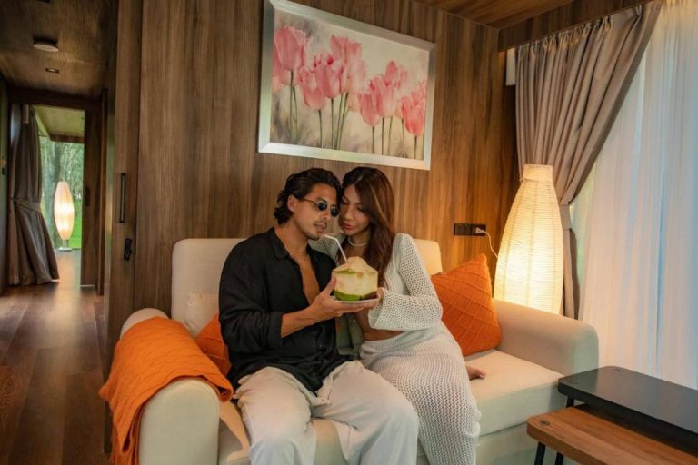 Pareja romántica compartiendo un coco fresco en el salón acogedor del Timber Society Boutique Hideaway