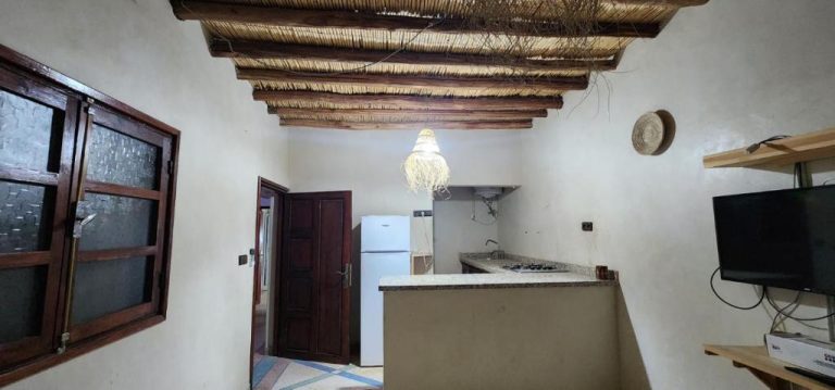 Cocina equipada con nevera y encimera en Auberge Dar Laazouzi con techo de cañas tradicional