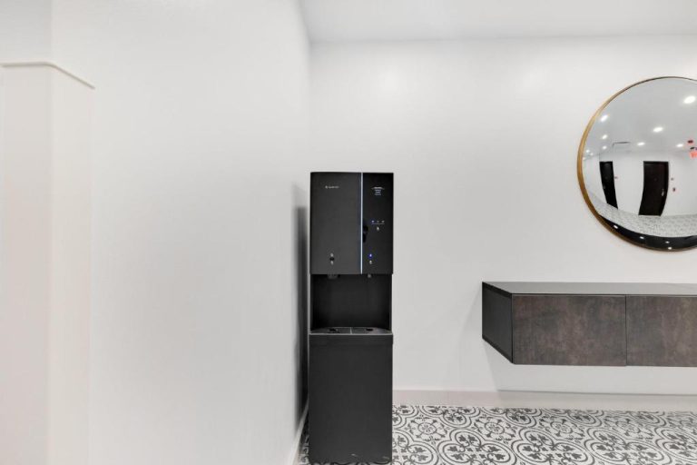 Dispensador de agua moderno en negro en la recepción del Hotel Milano con espejo dorado decorativo
