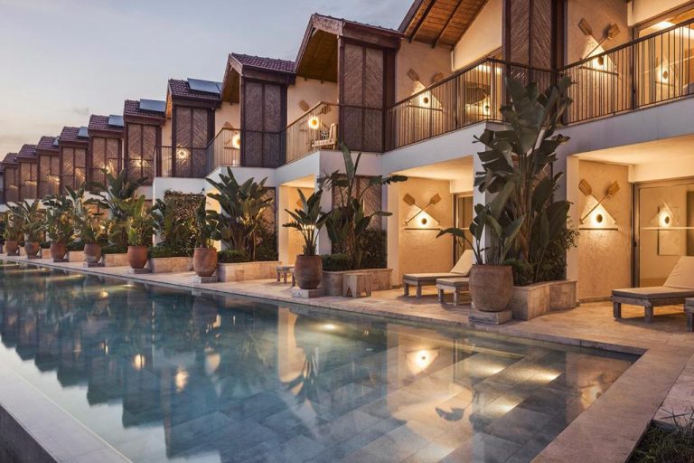 Piscina exterior iluminada al atardecer del Day One Beach Resort & SPA Adult Only con bungalows y palmeras