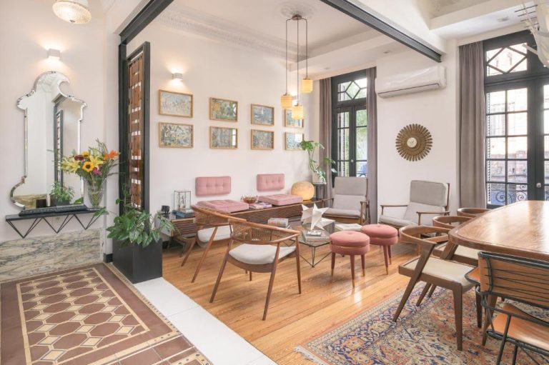 Salón con decoración vintage y muebles de madera en FAUNA Montevideo, con cuadros y sillas retro