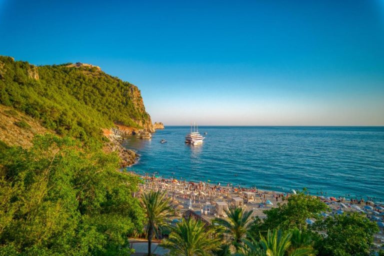 Playa privada con tumbonas y barco en el mar turquesa del hotel La Gaia Adult Only