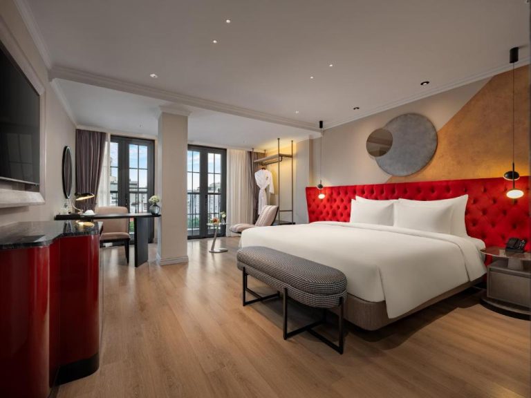 Habitación deluxe con lujoso cabecero rojo capitoné y cama king size en Grand Hotel du Lac Boutique Saigon