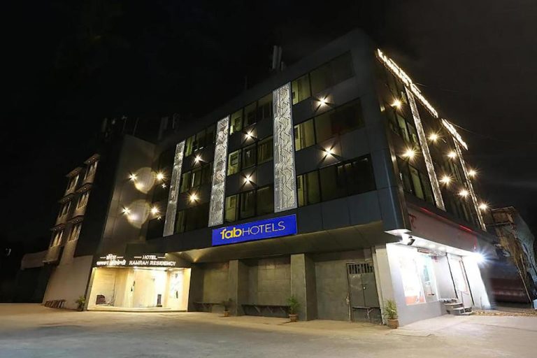 Fachada iluminada de noche del FabHotel Kamran Residency cerca de LBS Marg con decoración exterior