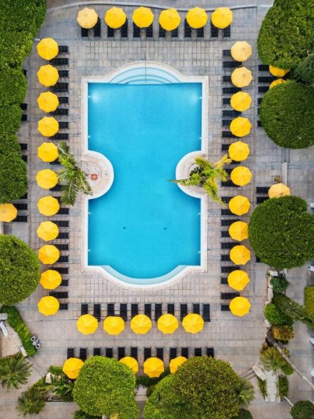 Vista aérea de la piscina exterior del Mayfair Hotel rodeada de tumbonas y sombrillas amarillas