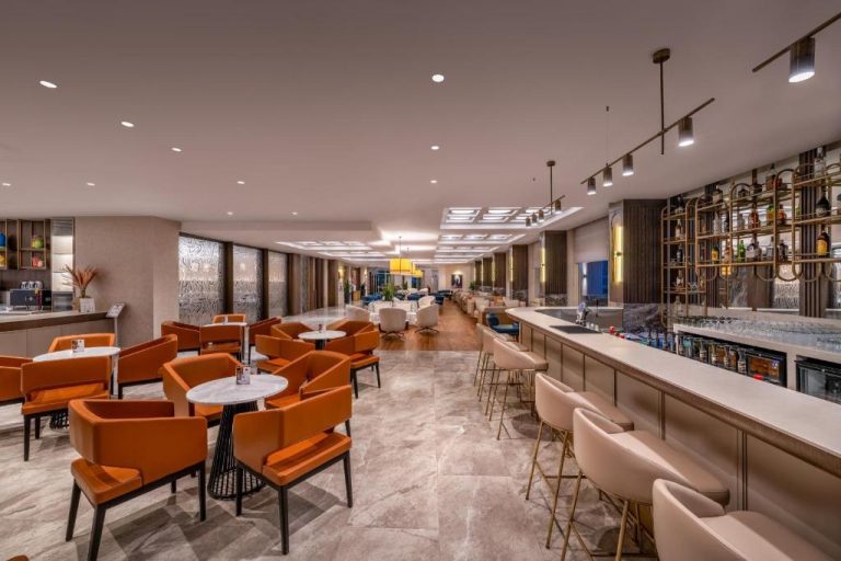 Bar y salón lounge del Trendy Palm Beach Adults Only con sillas naranjas y barra iluminada
