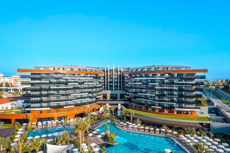 Vista aérea de la piscina exterior con tumbonas y palmeras del Calyptus Kirman Premium Ultra All Inclusive