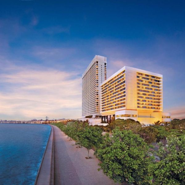 Vista exterior del The Oberoi Mumbai con paseo marítimo al atardecer frente a la bahía de Mumbai