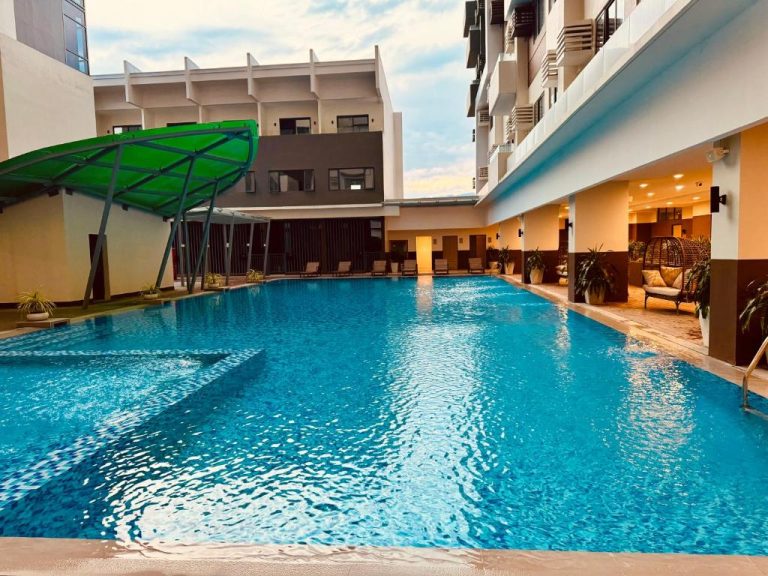 Amplia piscina exterior con tobogán verde del LD Cozy Condo Unit cerca del Cebu IT Park