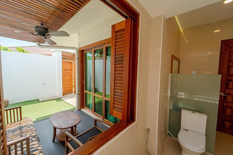 Baño privado con terraza exterior y jardín en Telaga Village Resort con ventana de madera