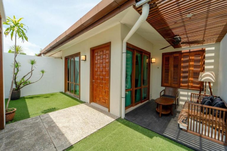 Terraza y jardín privado con césped verde y mobiliario de madera en Telaga Village Resort