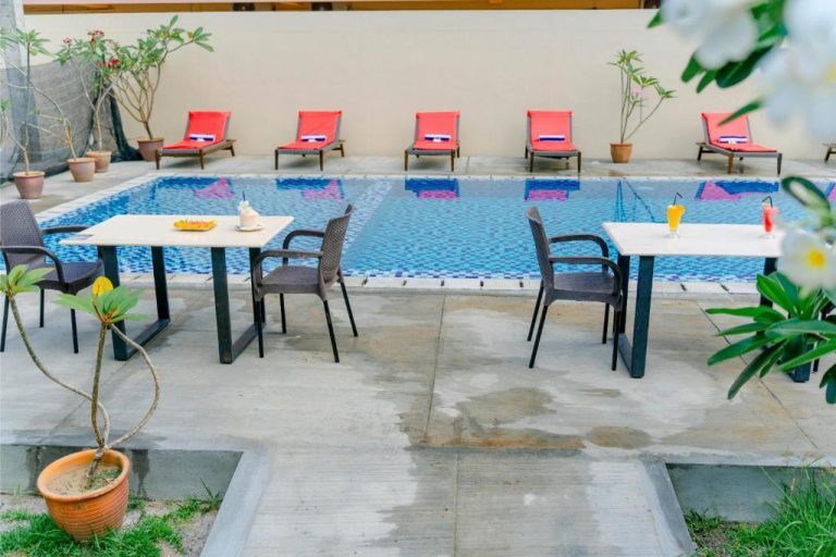 Piscina exterior con tumbonas rojas y mesas junto al agua en Telaga Village Resort