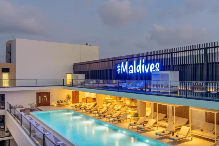 Piscina rooftop con tumbonas y zona lounge del hotel Barceló Nasandhura Malé en Maldivas
