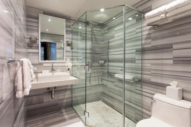 Baño moderno con ducha de cristal y revestimiento de mármol gris en Hotel El Convento