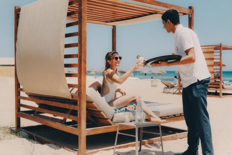 Servicio de bebidas en cabana de playa del Iberostar Selection Eolia Djerba con tumbonas y vistas al mar