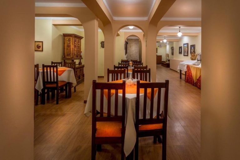 Restaurante interior del Katari Plaza Cusco El Virrey con mesas decoradas en naranja y sillas de madera