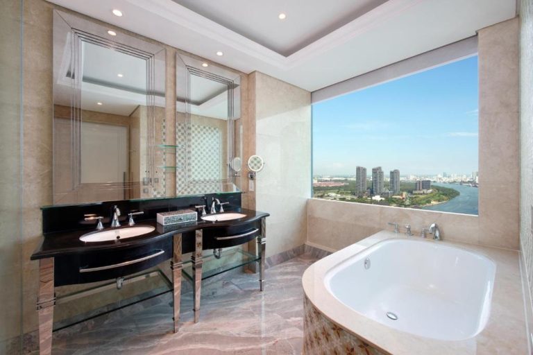 Baño de lujo con bañera y vistas panorámicas al río en The Reverie Saigon Residential Suites