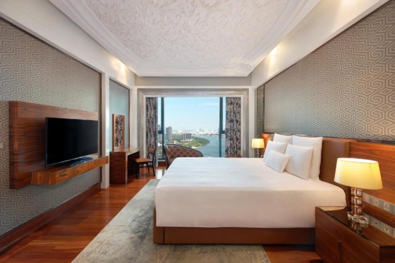 Suite de lujo con cama king, TV y vista panorámica al río en The Reverie Saigon Residential Suites