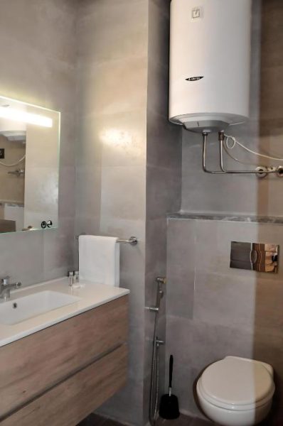 Baño moderno con lavabo, inodoro y calentador de agua en Dominium Residence