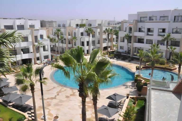 Vista aérea de la piscina exterior con palmeras y zonas de descanso en Dominium Residence