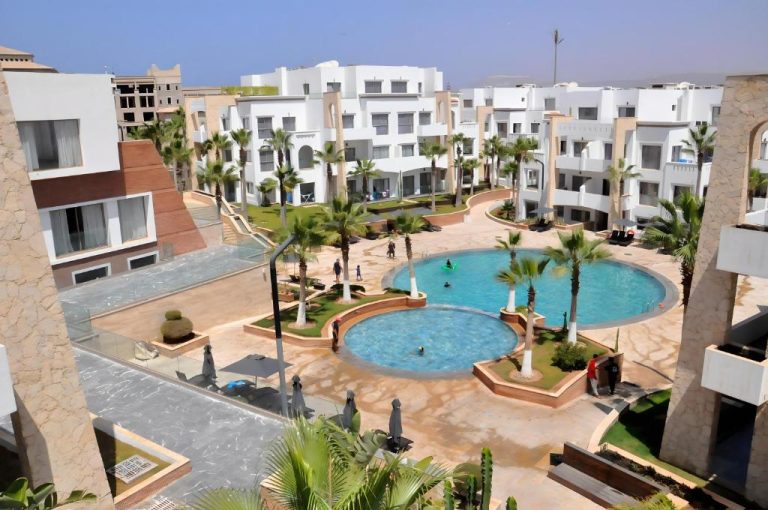 Piscinas exteriores con palmeras y jardines del Dominium Residence vistas desde terraza superior
