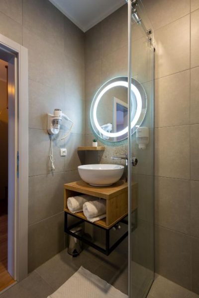 Baño moderno con ducha de cristal y espejo LED circular en Plitvice Village