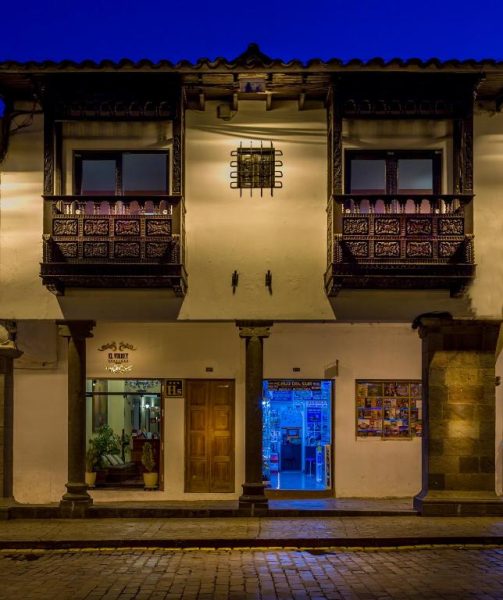Fachada colonial nocturna del Hotel Katari Plaza Cusco El Virrey con balcones tallados en madera