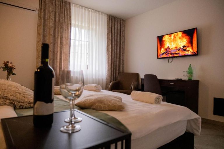 Habitación doble con chimenea en TV, botella de vino y copas en Plitvice Inn