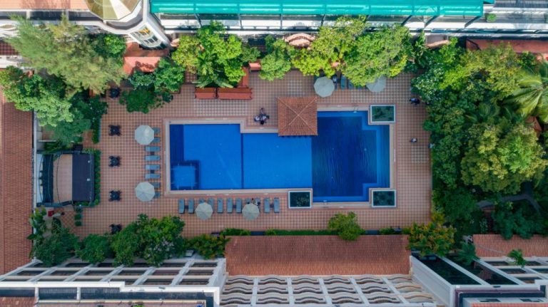 Vista aérea de la piscina exterior con tumbonas y jardines tropicales del Hotel Somadevi Angkor Resort & Spa