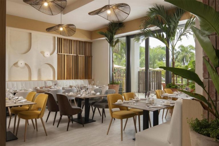 Restaurante interior con sillas amarillas y vegetación tropical en Royal Beach Hotel Punta Cana by Hyatt